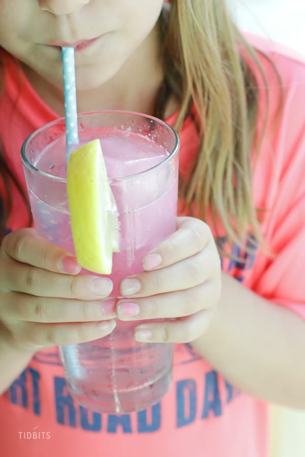 A child holding a glass of fizzy drink with a straw