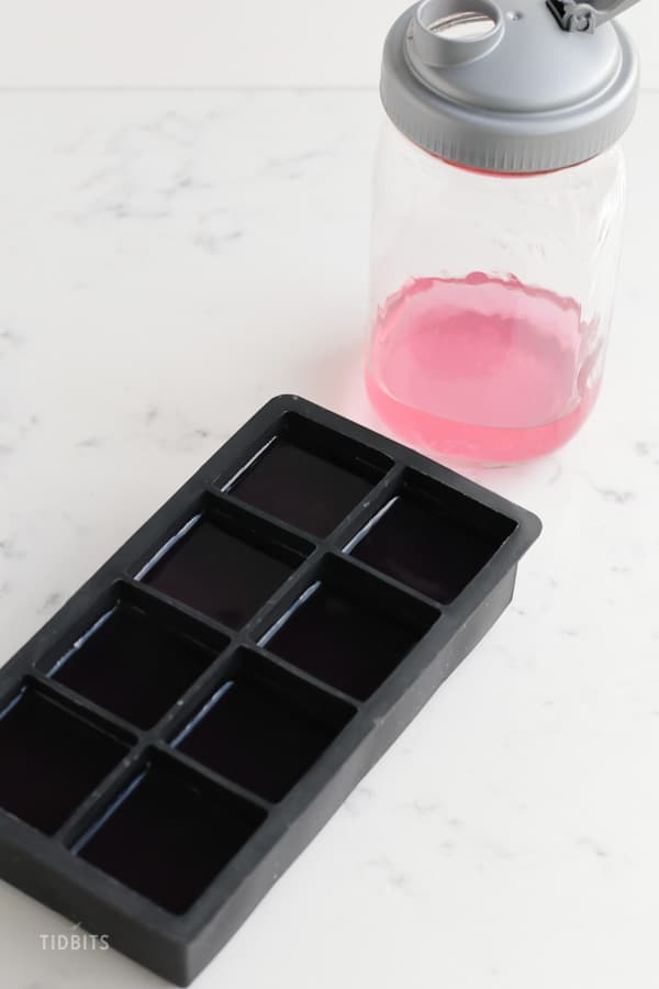A bottle of infused water next to an ice cube mould