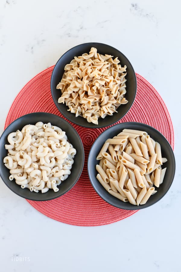Three bowls of pasta on a red mat - TIDBITS Marci