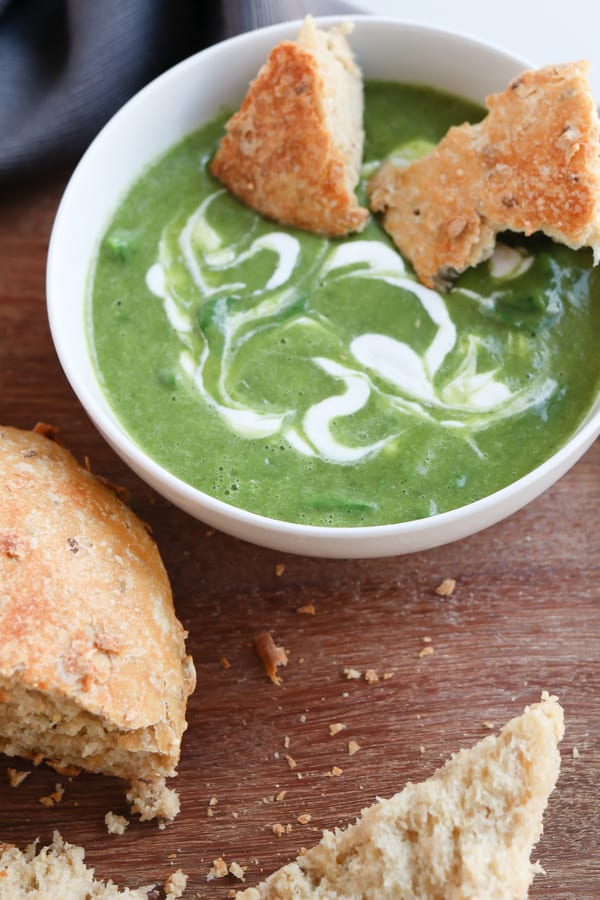 Torn up pieces of bread in a bowl of green soup