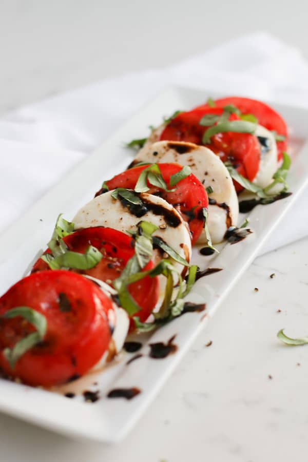 Pressuer cooker mozzarella on a white serving plate with tomatoes and balsamic dressing