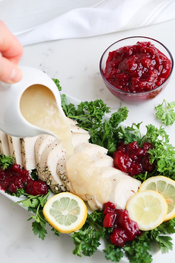 Sliced Turkey on a plate with parsley, lemons, and cranberries