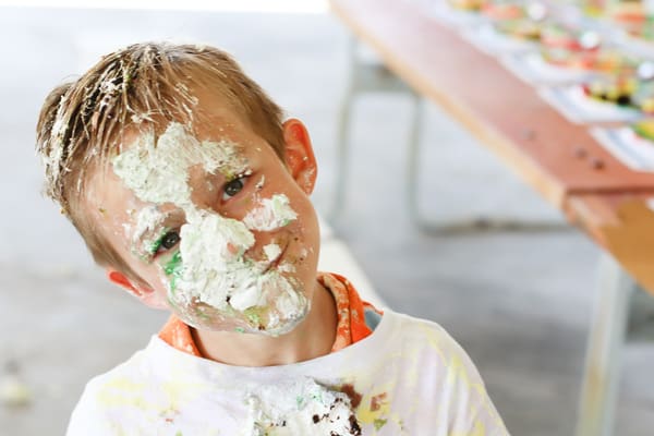 A child with cake on his face looking at camera