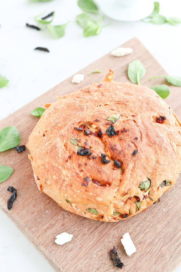 Instant Pot Sun-Dried Tomato, Feta, and Spinach No Knead Crusty Bread on a wooden chopping board