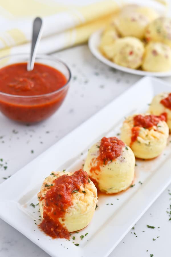 Sous vide eggs on a white serving plate drizzled with red sauce