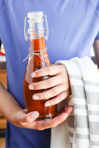 Instant Pot Peach Chipotle BBQ Sauce in a bottle held by a girl