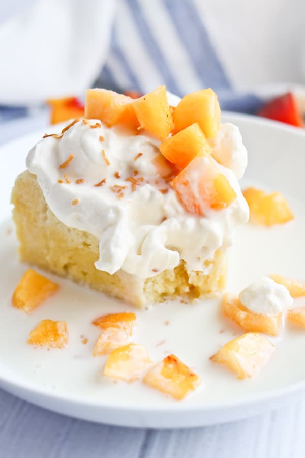 tres leches cake with peaches and cream in a white bowl