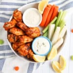 chicken wings on a plate with carrots and celery