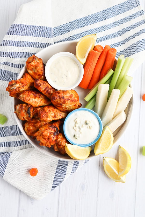chicken wings on a plate with carrots and celery