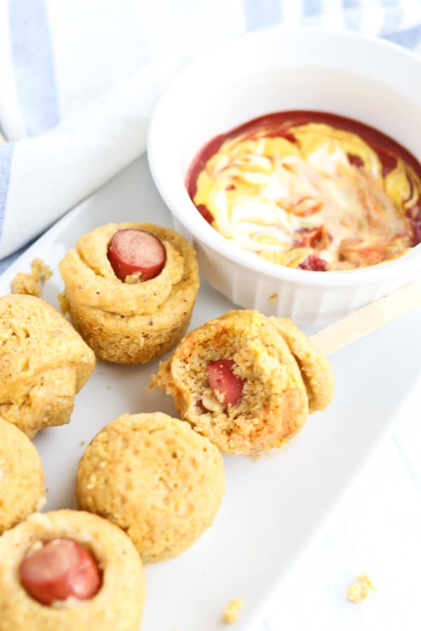 Corn dog muffins on a white platter with ketchup and mustard dip