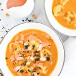 butternut squash soup in a white bowl with peanuts and basil