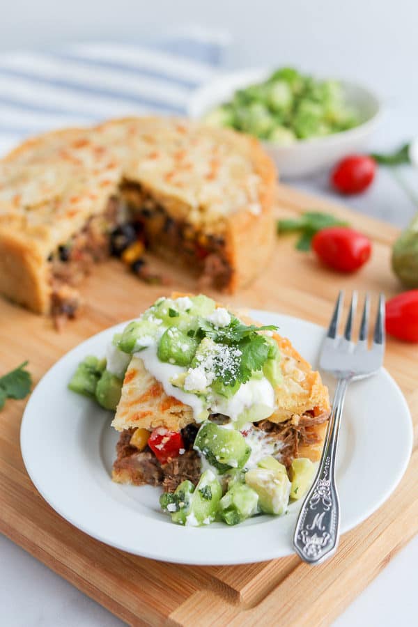 Slice of tamale pie with sour cream and green salsa over top