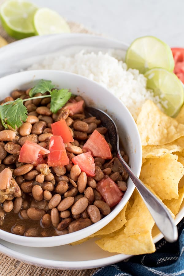 Instant Pot pinto beans in a white bowl with tomatoes on top