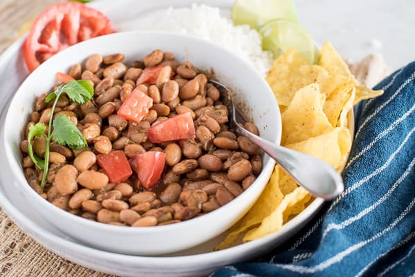 Instant Pot pinto beans in a white bowl with tomatoes on top