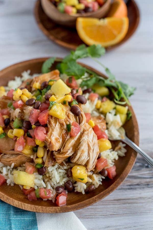 Instant Pot Orange Chicken with Mango Black Bean Salsa over rice on a wood plate