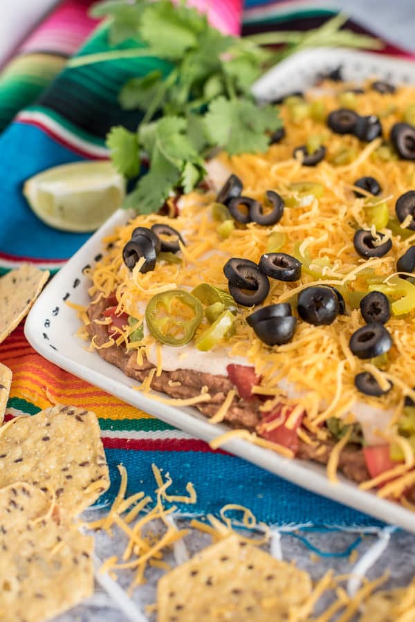 Plate of 7 layer bean dip with cheese and olives on top