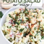 Potato Salad in a white bowl topped with herbs and paprika