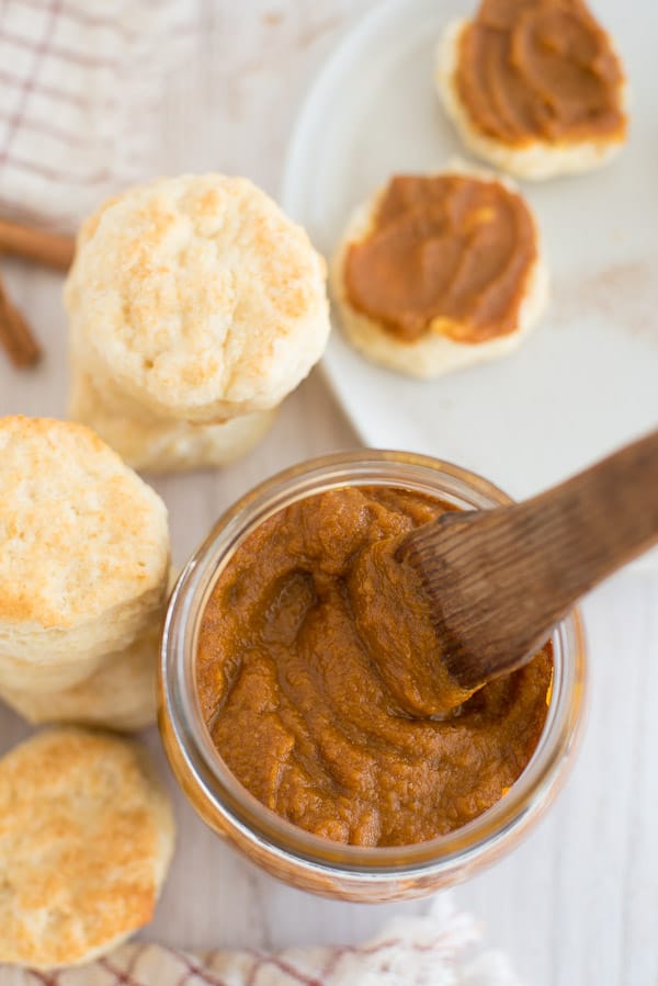 pumpkin butter in a jar with a spoon and biscuits on the side