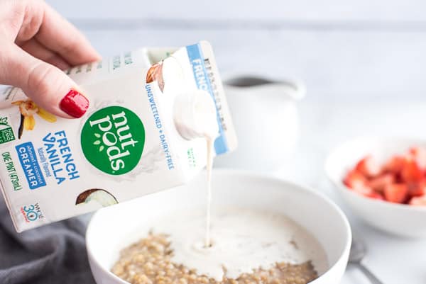 carton of dairy free creamer being poured into a bowl of oats