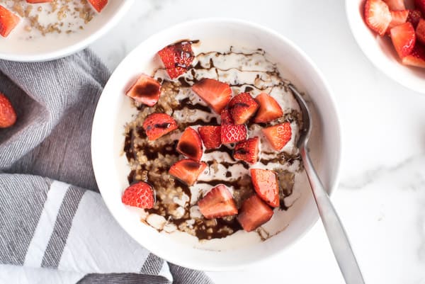 Bowl of steel cut oats with strawberries, cream, and chocolate