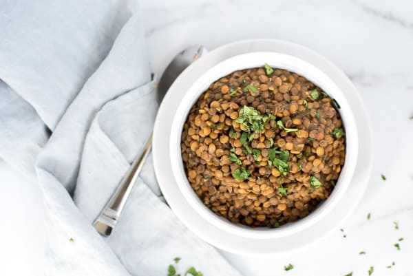 Instant Pot Lentils in a white bowl garnished with parsley
