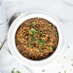 Instant Pot Lentils in a white bowl garnished with parsley