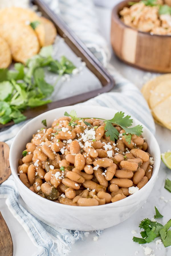 White bowl with beans, cilantro and lime with a sprinkle of cotija cheese