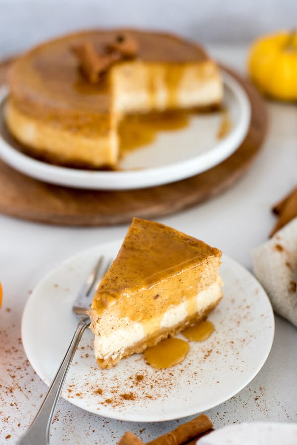 Slice of pumpkin cheesecake on a white plate with pumpkins