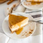Slice of pumpkin cheesecake on a white plate with pumpkins