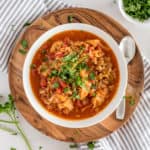 cabbage roll soup in a white bowl with a garnish of herbs