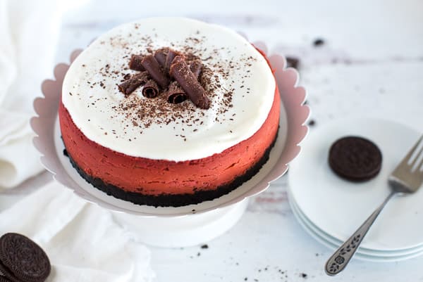 red velvet cheesecake on a white plate with chocolate curls