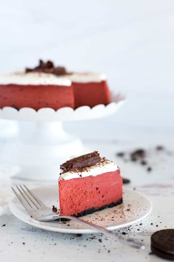 Slice of red velvet cheesecake on a white plate with a fork