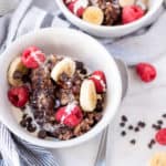 Two white bowls of chocolate oatmeal with bananas and berries