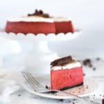 Slice of red velvet cheesecake on a white plate with a fork