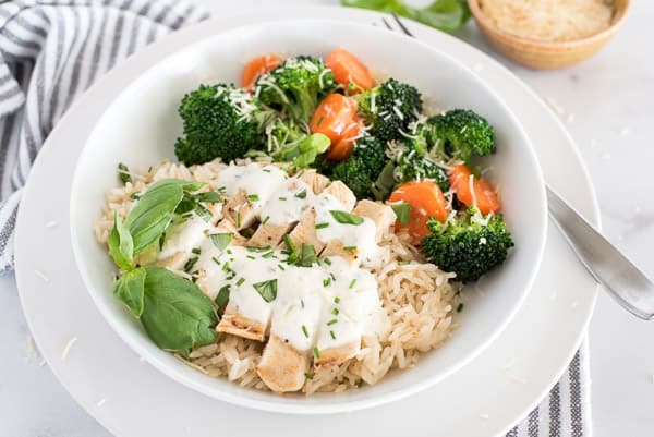 white plate with chicken, broccoli, and carrots with cheese sauce