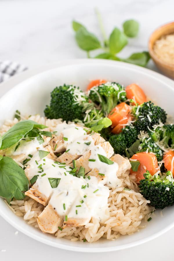 white plate with chicken, broccoli, and carrots with cheese sauce