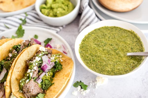 steak taco with a side of chimichurri sauce topped and guacamole