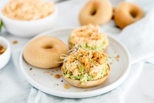 bagel with chickpea salad on it with sprouts and pepper.