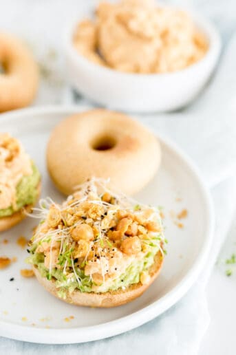 bagel with chickpea salad on it with sprouts and pepper.