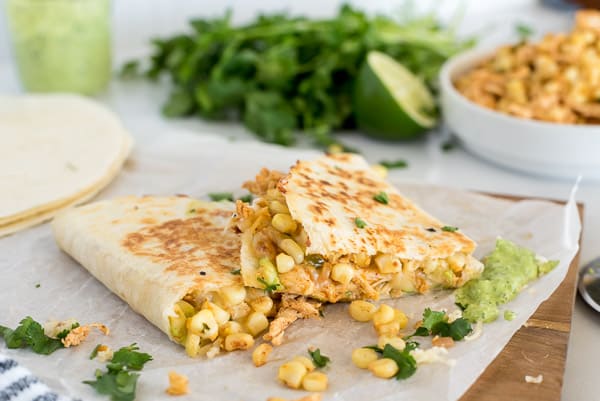 street corn quesadillas with avocado on a cutting board with lime