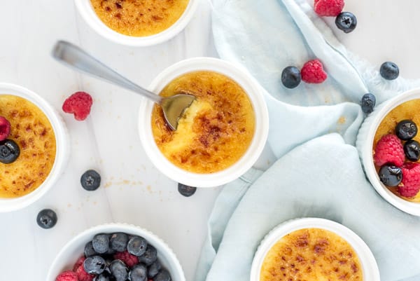 creme brulee in a white ramekin with a golden crust topping and berries