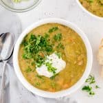Instant Pot split pea soup in a white bowl garnished with parsley and sour cream